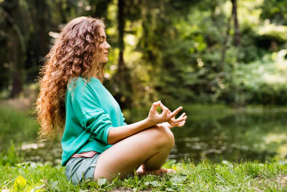 Young girl meditating in the woods