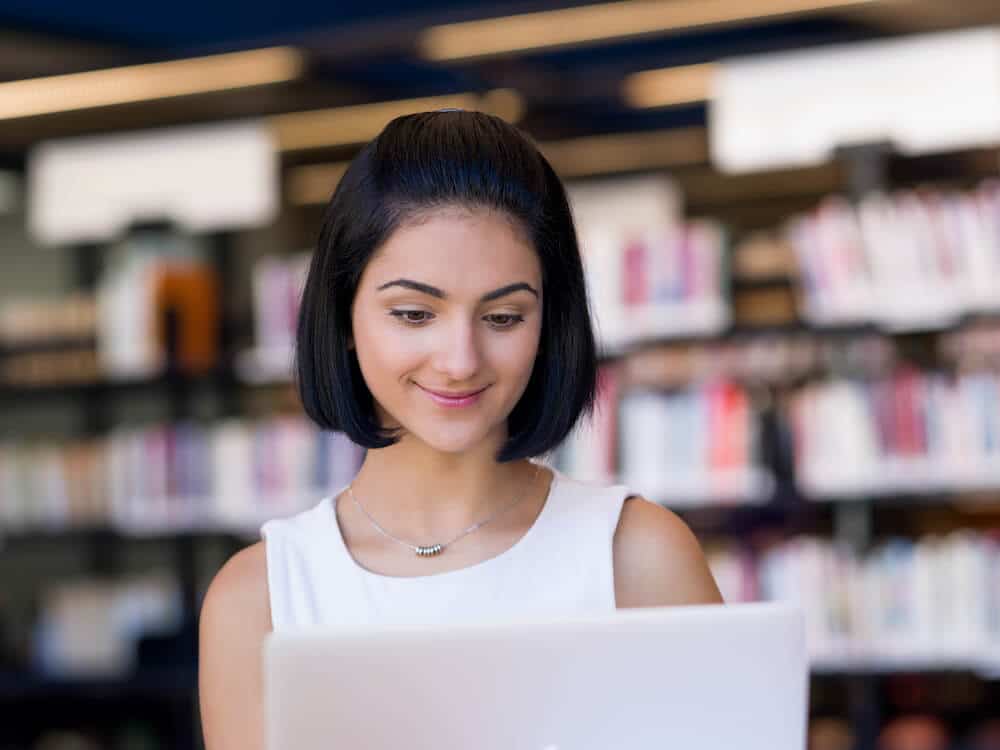 Student after submitting and reviewing their college applications smiling at their laptop