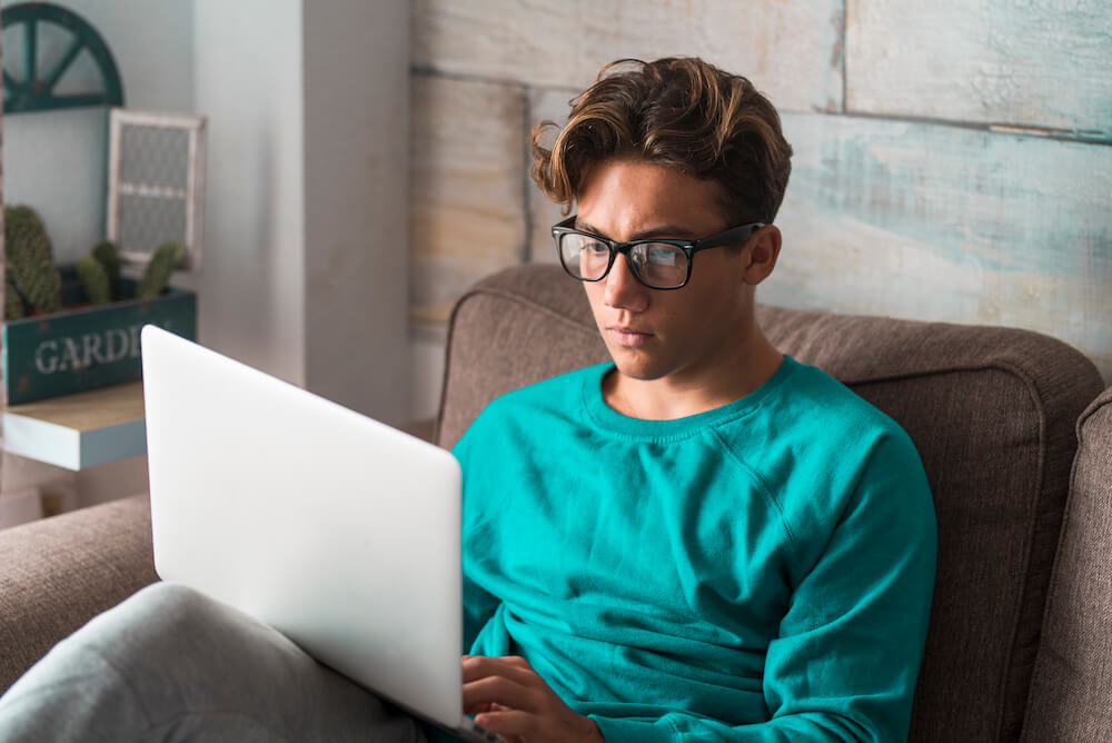 Teen working on their laptop in a living room