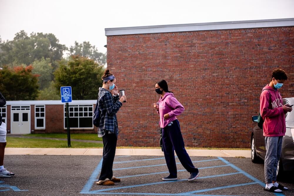 Students walking out from school wearing masks and staying 6 feet away
