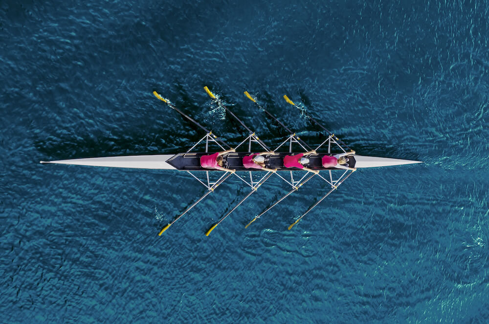 Overhead view of 4 students rowing in a body of water | Command Education
