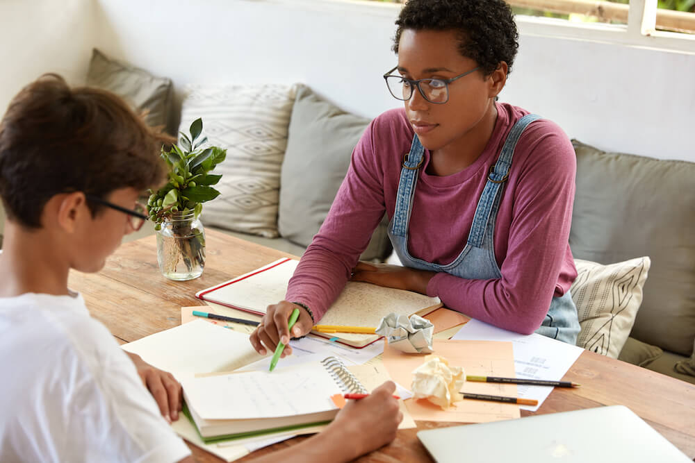 Tutoring, education and encouragement concept. Serious black female tutor conducts geometry class with trainee who has individual tutoring lesson, work one to one, prepare for final examination.