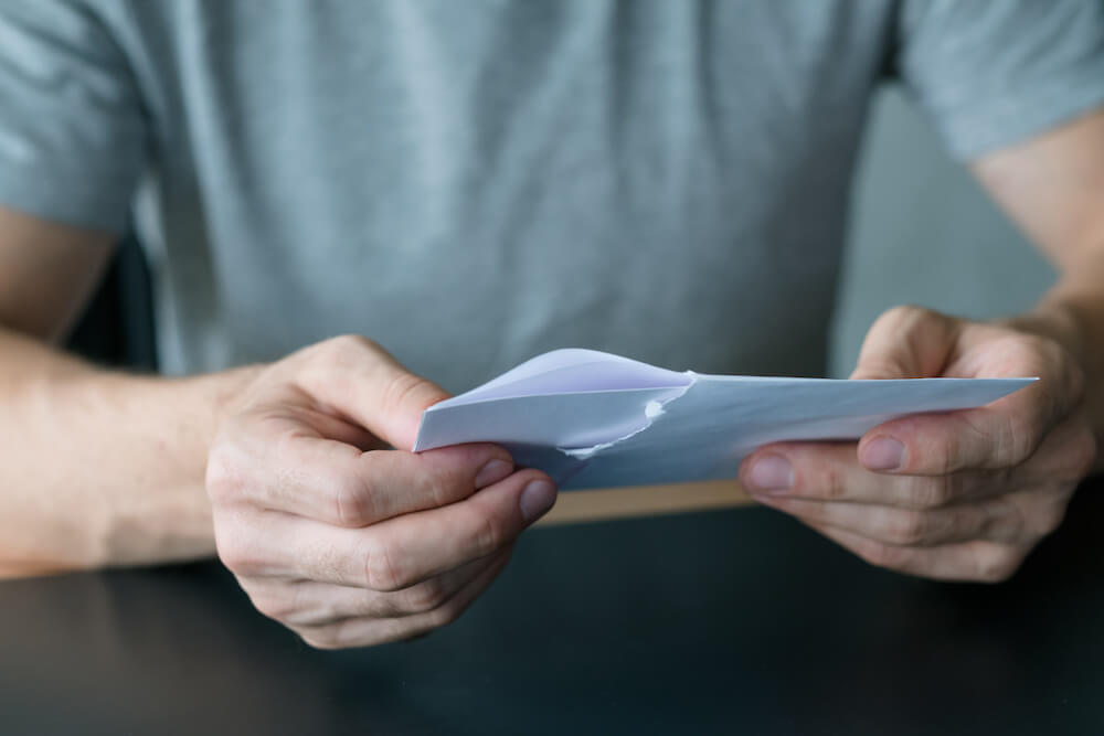 Cropped shot of man taking out received admissions letter from envelope for UC.