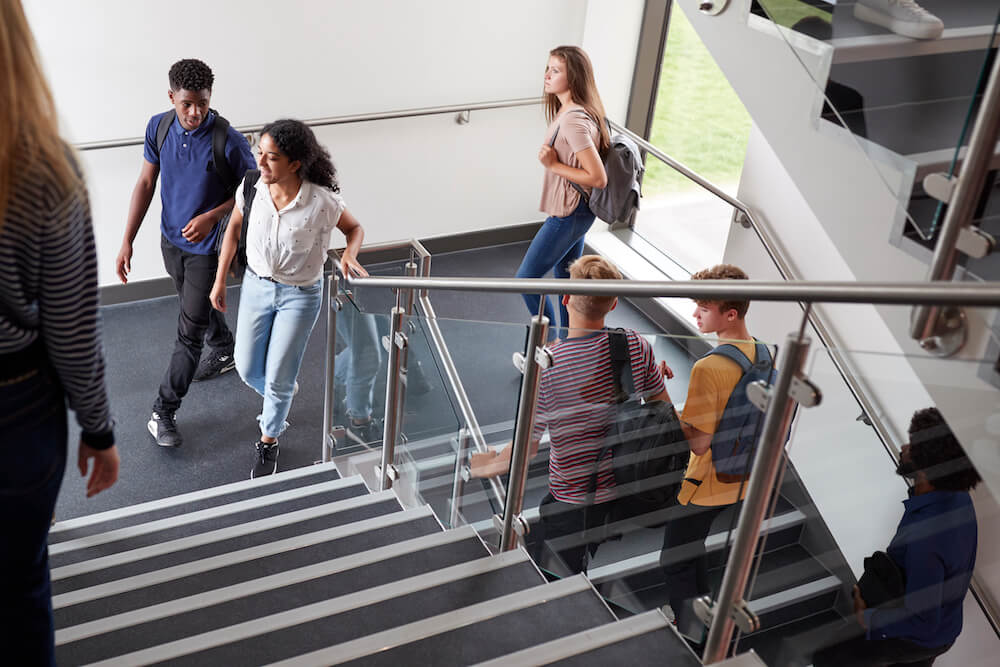 High School Students Walking On Stairs Between Lessons In Busy College Building