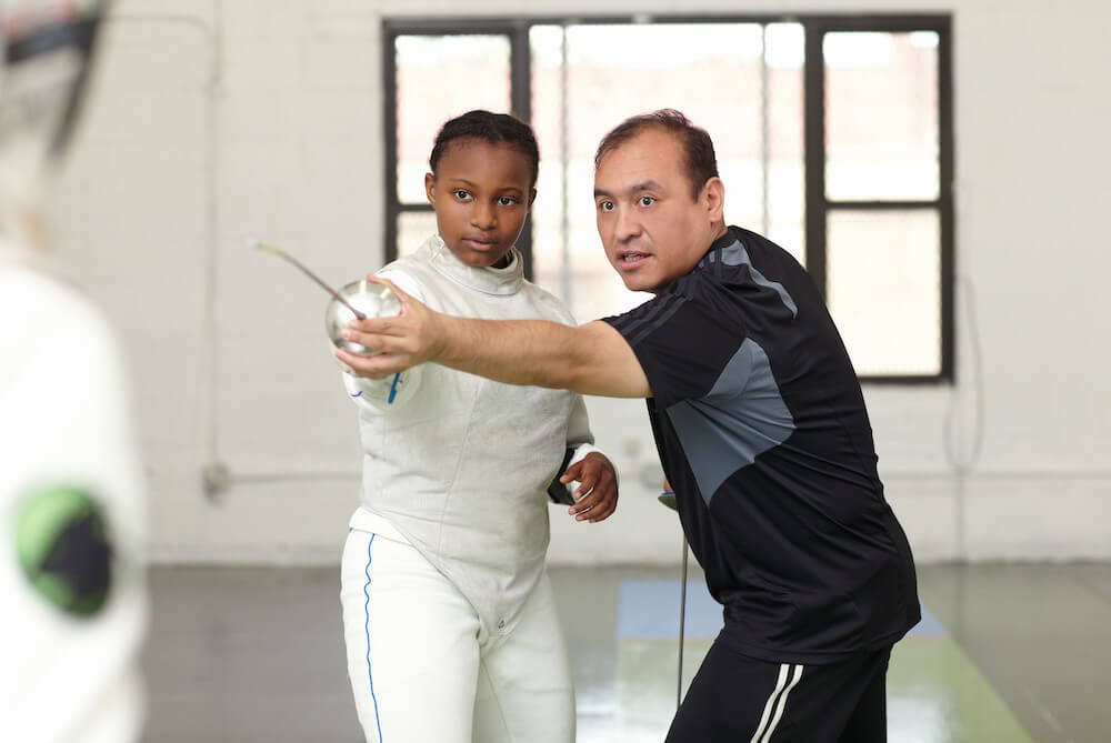 Fencing tutor assisting female student