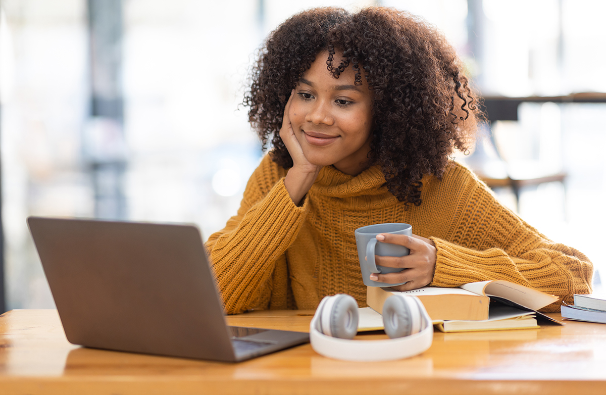 girl sitting at desk looking at laptop grinning as she was accepted to college