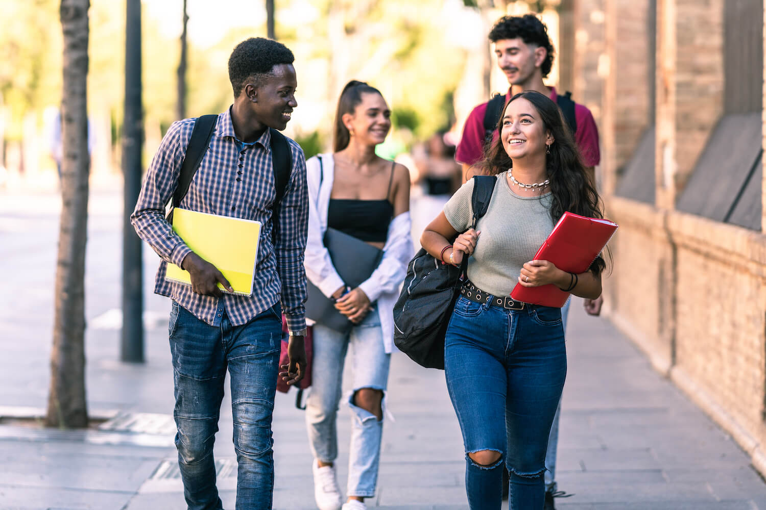 Four Students all walking together on a high school campus in the sun. Command Education