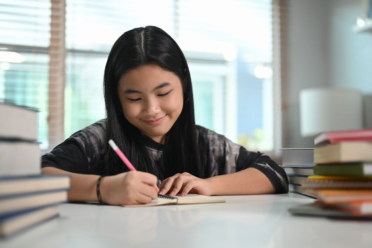 brag sheet, Smiling teenage girl completing recommender's brag sheet at desk.