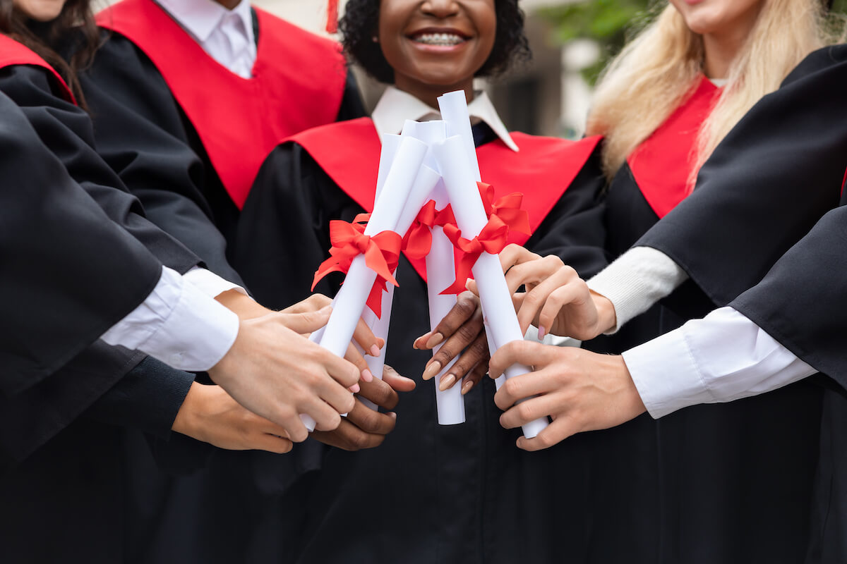 Cropped of multiracial group of students joining their diplomas together