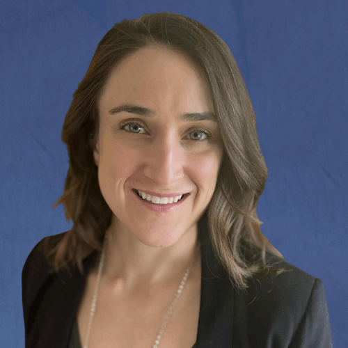 Jen, Senior Mentor, wearing a black blazer and pearl necklace, smiling in front of a gold-patterned background