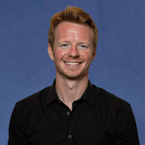 Nicholas, Research & Data Coordinator, wearing a black button-down shirt, smiling with teeth