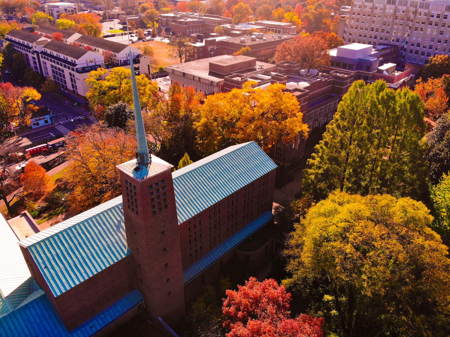 Aerial view of the brick General Theological Seminary building with fresh blue metal roofs, surrounded by autumn foliage at Vanderbilt University.
