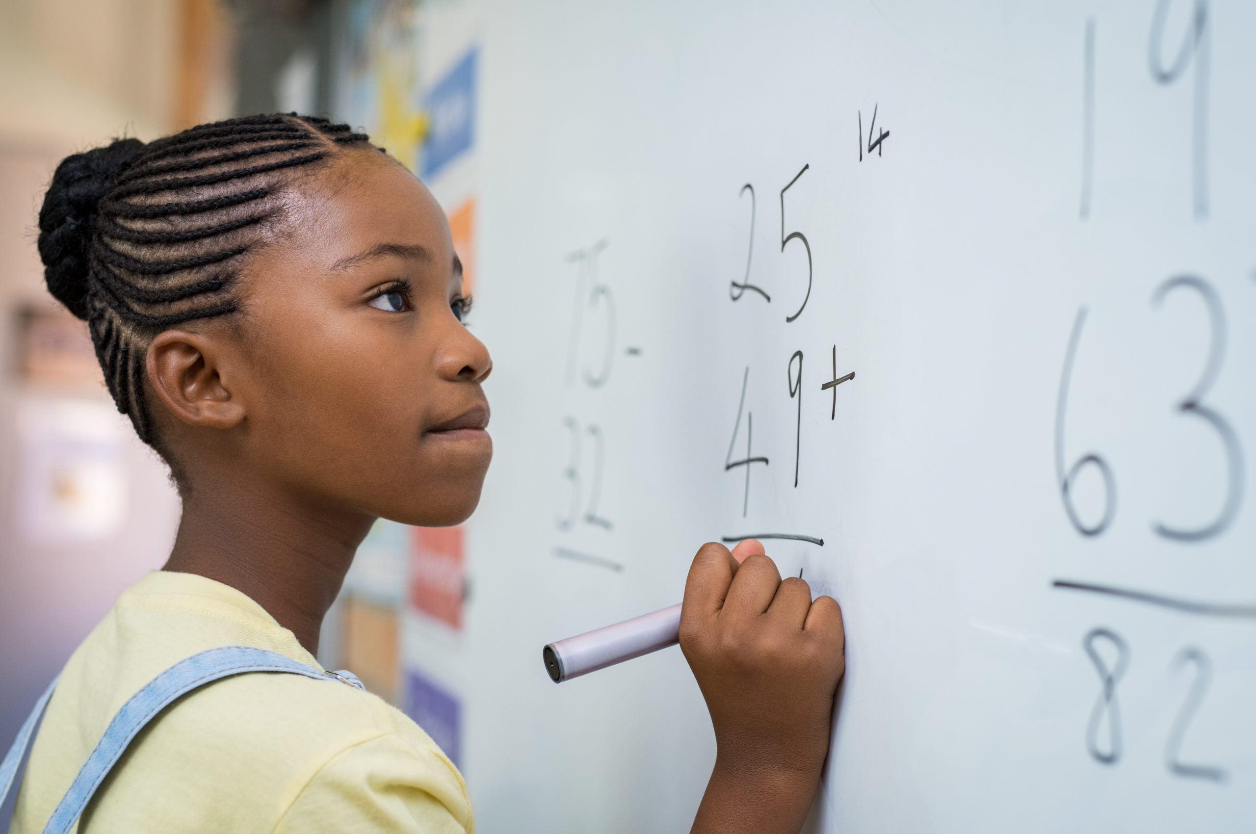 Young girl solving a math problem on a white board