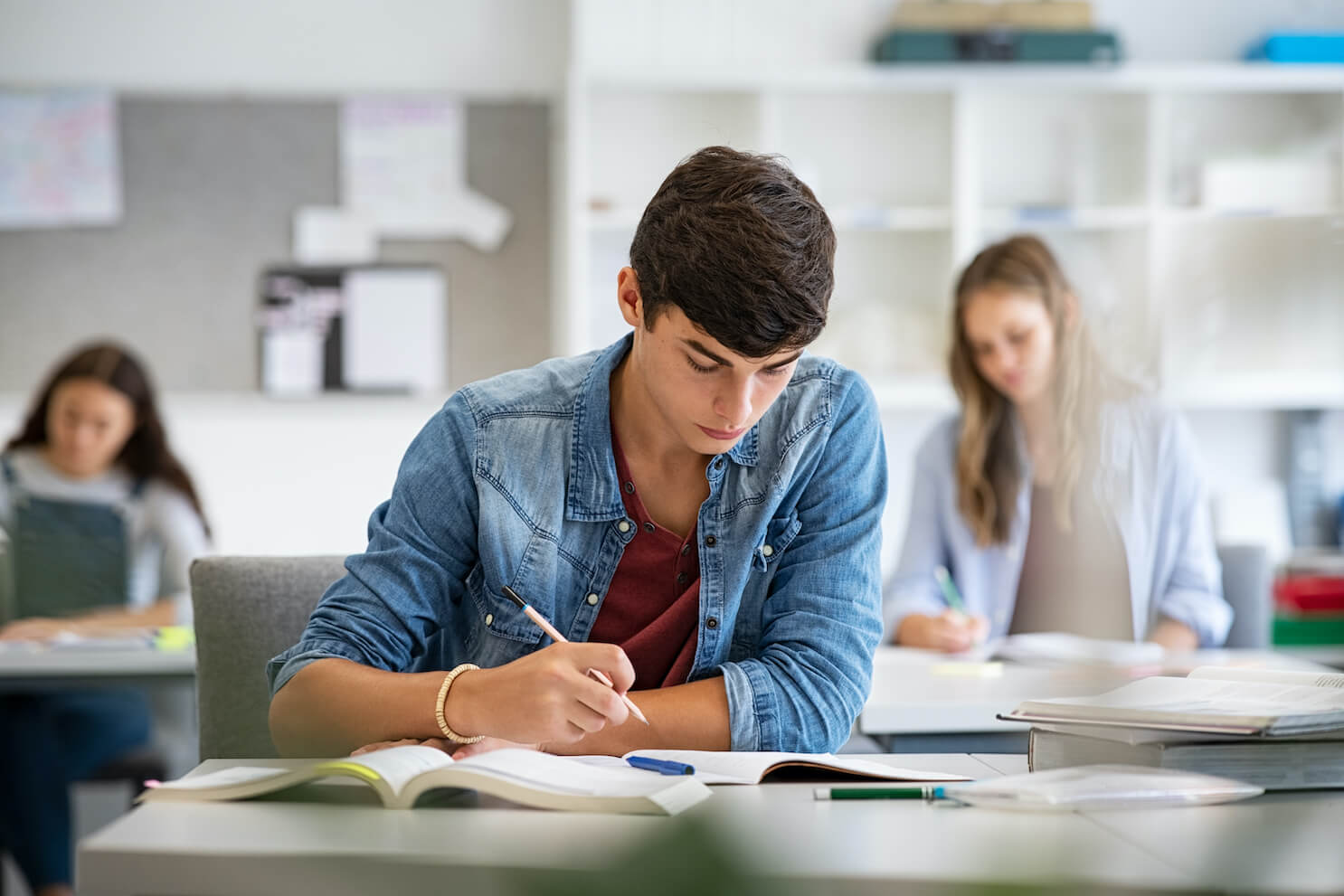 Teen student studying in a classroom with other students